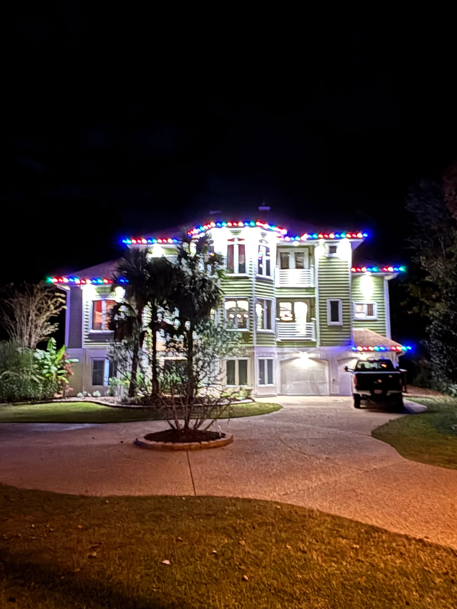Colonial home with professional RGB LED holiday lights outlining roofline and architectural features at night