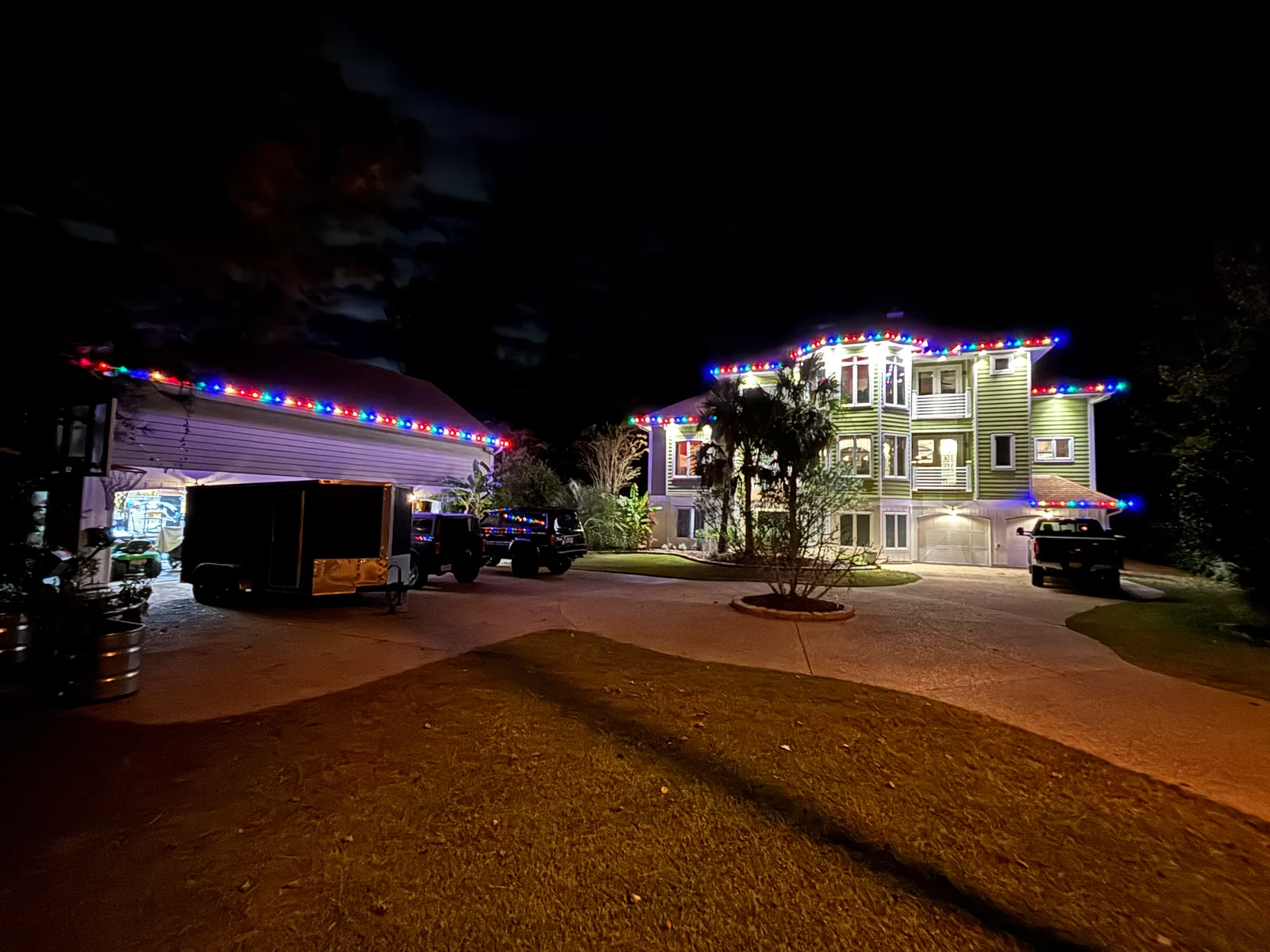Pressure-washed driveway and holiday light installation on residential home with multi-colored LED strings