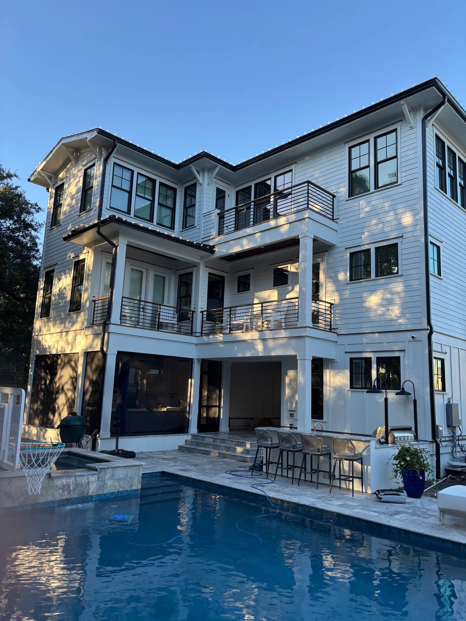White modern home with cleaned siding, railings, and patio deck overlooking pool
