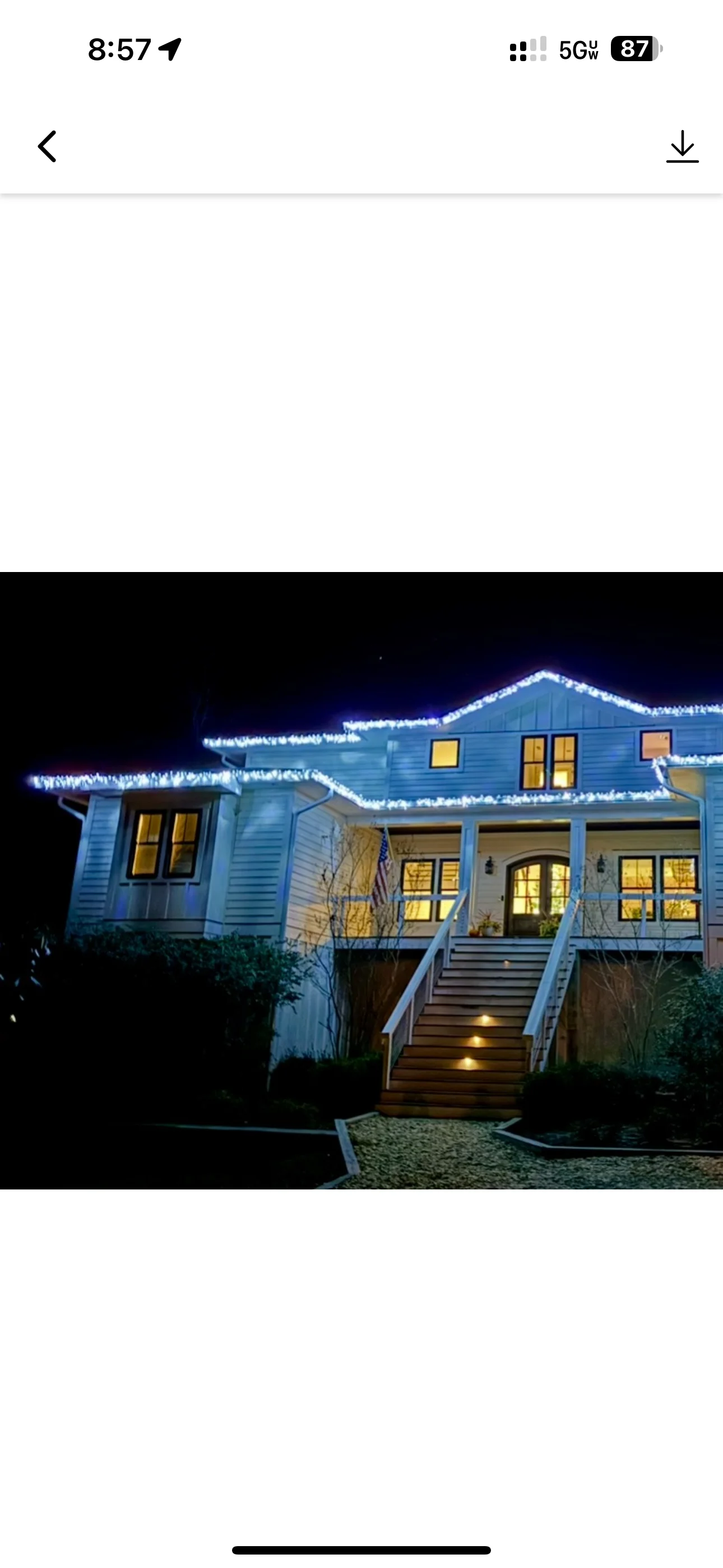 Two-story blue vinyl siding home with deck stairs, cleaned exterior and illuminated windows at night